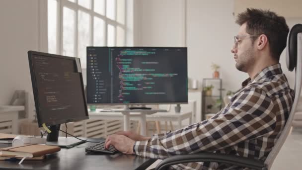 Boční zobrazení záběru profesionálního správce systému nebo vývojáře softwaru psaní programových kódů na počítači PC pracuje sám v moderní kanceláři - Záběry, video
