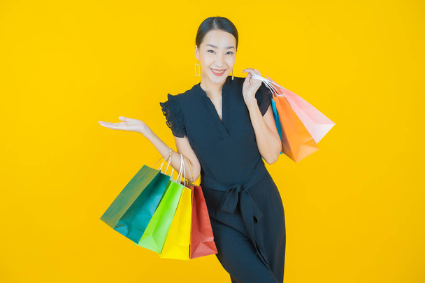 Muotokuva kaunis nuori aasialainen nainen hymyillä ostoskassi värillinen tausta - Valokuva, kuva