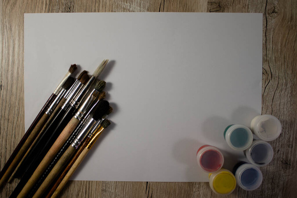 Paint brushes with watercolors for painting on a white sheet of paper. - 写真・画像