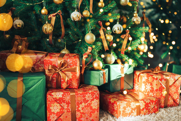 Много подарочных коробок, стоящих под украшенной елкой - Фото, изображение