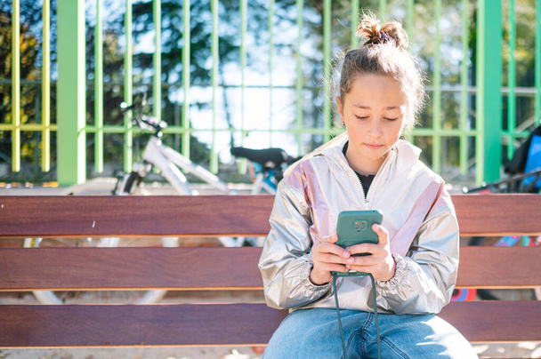 Teen girl using smartphone outdoors. - Valokuva, kuva
