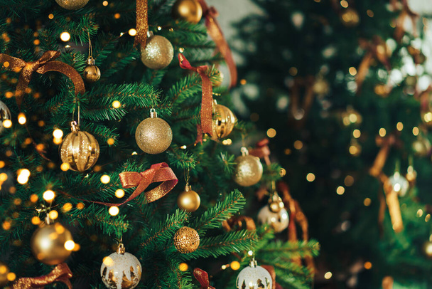 Green artificial tree is hung with baubles and garland - Photo, Image