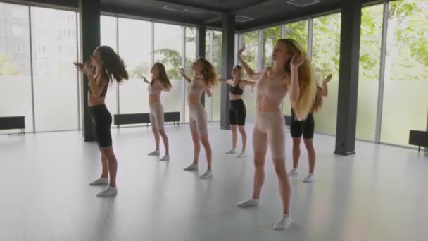 Grupa elastycznych kobiet trening z trenerem w studio tańca, ćwiczenia pochylenia pas w świetlicy, śledzenie strzał - Materiał filmowy, wideo