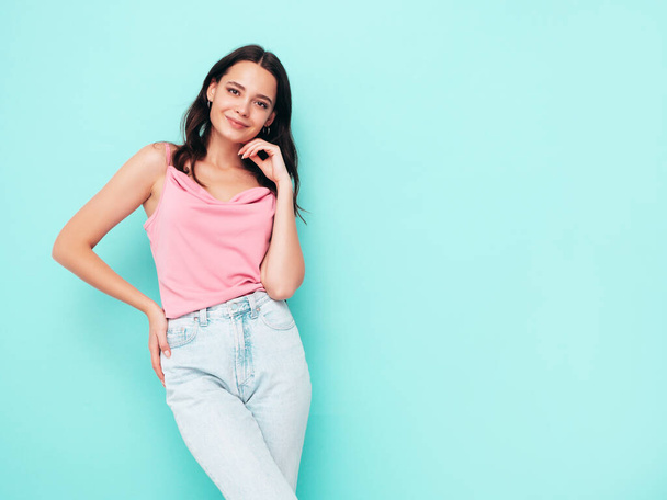 Young beautiful smiling female in trendy summer clothes. Sexy carefree woman posing near blue wall in studio. Positive brunette model having fun and going crazy. Cheerful and happy  - Φωτογραφία, εικόνα