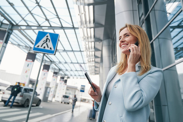 Passenger with boarding ticket talking on smartphone outdoors - Valokuva, kuva