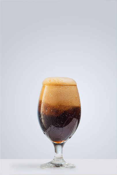 灰色の背景に隔離された濃い泡状のビールのガラス。アルコール飲料、パーティーの概念 - 写真・画像