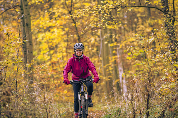 nice senior woman riding her mountainbike on the autumnal forest trails near Stuttgart, beautiful warm colors, Baden-Wuerttemberg, Alemanha - Foto, Imagem