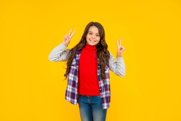peace gesture. glad teen girl has long curly hair. back to school. female fashion model. - Photo, Image