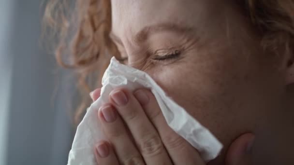 Close up of young caucasian  red head woman sneezing and blowing nose into tissue at home. Shot with RED helium camera in 8K.   - Footage, Video
