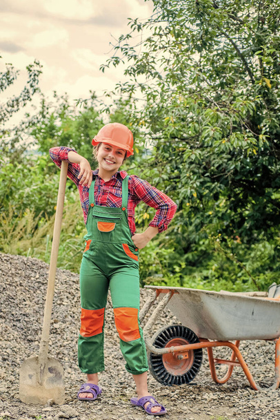 future engineer. happy kid use construction wheelbarrow. building construction site. child architect worker. labor day concept. childhood development. teenager girl assistant. transfer of experience - Fotografie, Obrázek
