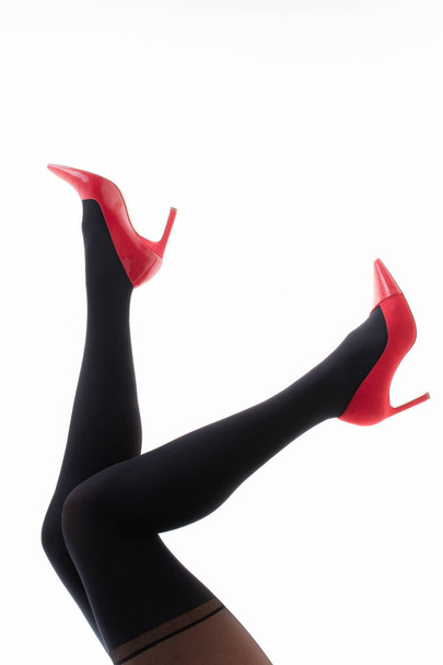 Feet of a girl in pantyhose with red shoes on a white background - Foto, immagini
