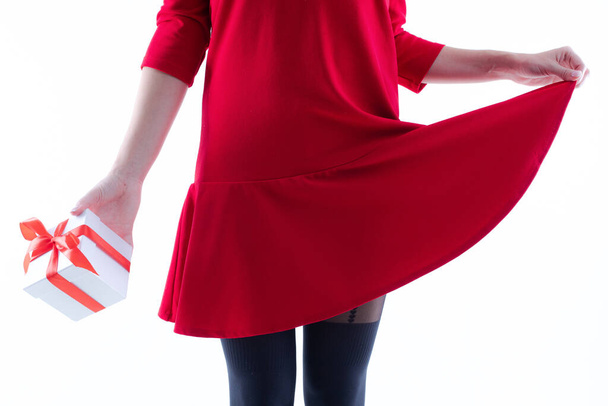 Young woman in a red dress and tights holds a gift in a box - Photo, Image