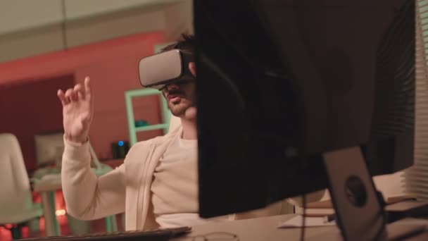 Slowmo seuranta laukaus nuori mies kuulokkeet kokee virtuaalitodellisuus pelaa tietokonepeliä pimeässä huoneessa - Materiaali, video