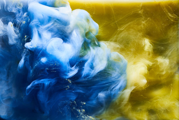 Blue yellow smoke on white ink background, colorful fog, abstract swirling ocean sea, acrylic paint pigment underwater - Foto, Imagen