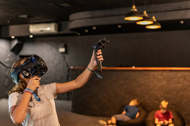 Das Mädchen im VR-Club spielt Spiele im 3D-Helm. - Foto, Bild