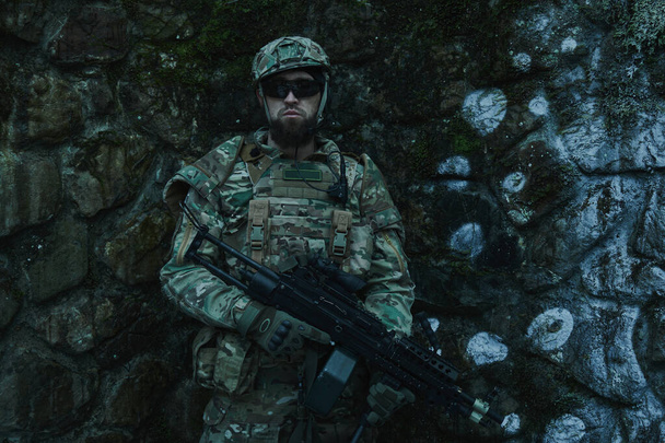 Portrait of airsoft player in professional equipment with machine gun in the forest. Soldier with weapons at war - Fotoğraf, Görsel