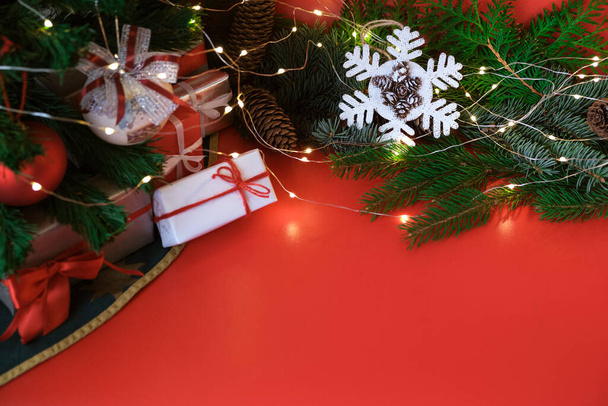 クリスマスグリーティングカードクリスマスの装飾:素朴なスタイル、ボール、贈り物、モミの枝、赤い背景のコーンで手作りの雪片。光でガーランド.選択的な焦点.スペースをコピー.トップビー - 写真・画像