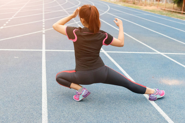 Νεαρή γυναίκα δρομέας τέντωμα πόδια πριν από το τρέξιμο - προπόνηση έννοια - Φωτογραφία, εικόνα