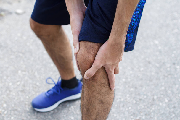 Close up of Sport man suffering with pain on sports running knee injury after running.Injury from workout concept. - Foto, Imagen
