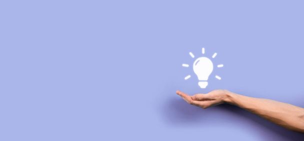 Hand hold light bulb. Holds a glowing idea icon in his hand. With a place for text.The concept of the business idea.Innovation, brainstorming, inspiration and solution concepts. - 写真・画像