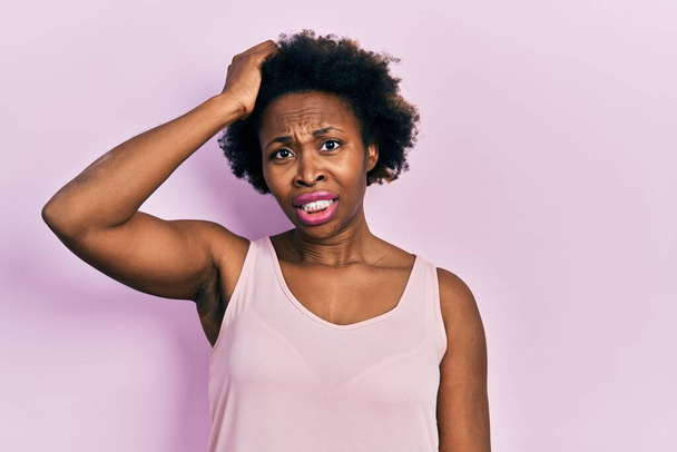 Young african american woman wearing casual sleeveless t shirt confuse and wonder about question. uncertain with doubt, thinking with hand on head. pensive concept.  - Photo, Image