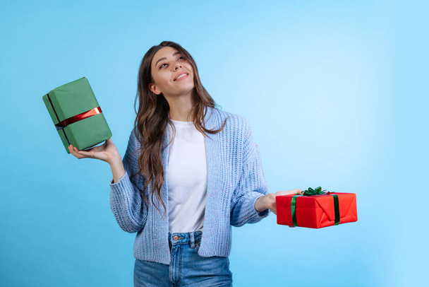 Excited young beautiful girl holding gift boxes isolated on blue studio background. Concept of emotions, Merry Christmas - Fotó, kép