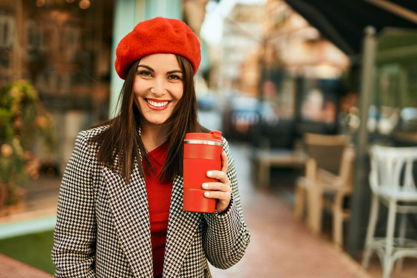 Młoda Latynoska uśmiechnięta szczęśliwa pijąca zabiera kawę do miasta. - Zdjęcie, obraz