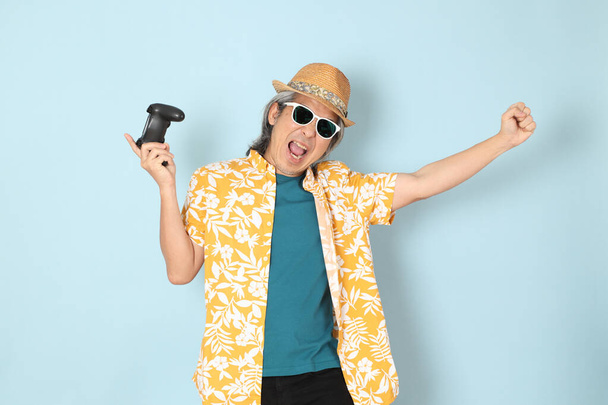 The senior Asian man wearing summer dressed standing on the blue background. - Photo, Image