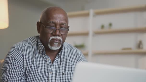 Онлайн работа для пожилых людей. Закрыть портрет старшего африканца-фрилансера в очках, печатающего на ноутбуке - Кадры, видео
