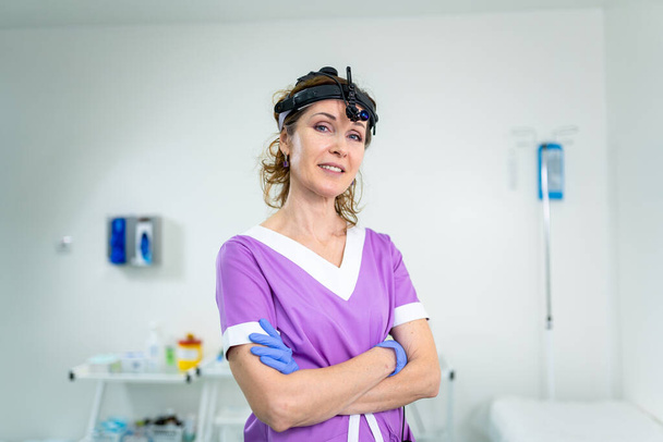 Beruf Medizinindustrie. Porträt einer HNO-Ärztin, die im Büro posiert, bevor sie Patientin untersucht. Arzt in heller Uniform mit medizinischen Geräten und Werkzeugen für die HNO-Praxis im Krankenhaus. - Foto, Bild