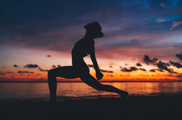 Silhouette of athlete with perfect pumped up figure recreating doing yoga poses feeling inner peace and vitality, female with flexible body standing in asana care about physical and mental health - Fotoğraf, Görsel