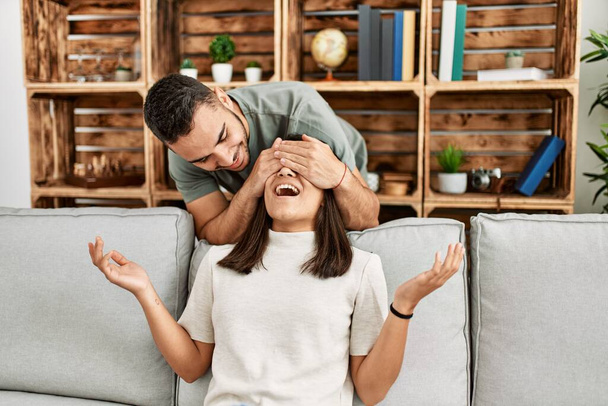 Homme surprenant sa petite amie avec les mains sur les yeux à la maison. - Photo, image