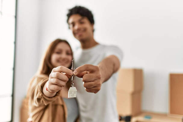 Young couple smiling happy holding key of new home. - 写真・画像