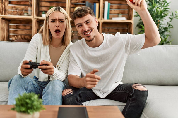 Joven pareja caucásica concentrada jugando videojuegos en casa. - Foto, Imagen