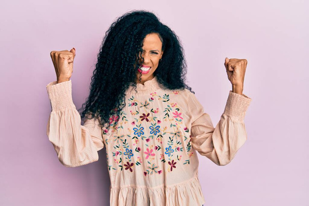 Middle age african american woman wearing casual clothes screaming proud, celebrating victory and success very excited with raised arms  - Foto, Bild