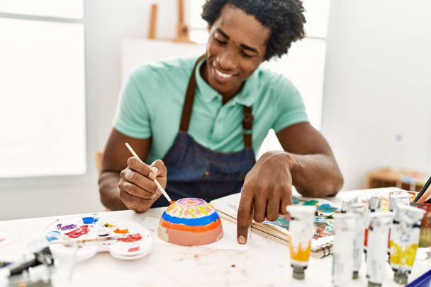 若いアフリカ系アメリカ人のアーティストがアートスタジオで陶芸を描く. - 写真・画像