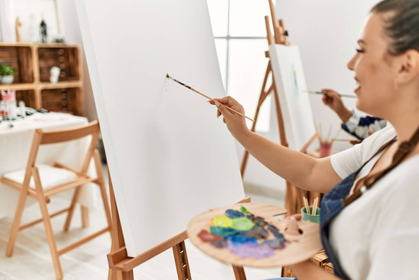 Junge Künstlerin Frau und Senior-Maler Mann im Kunststudio Klassenzimmer Malerei auf Leinwand mit Pinsel und Ölgemälde - Foto, Bild