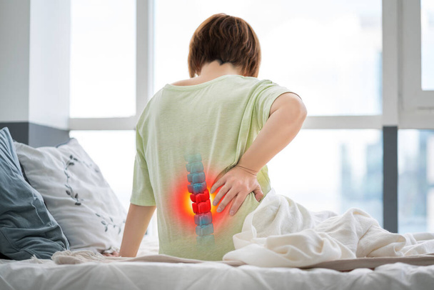 Lumbar intervertebral spine hernia, woman with back pain at home, spinal disc disease, health problems concept - 写真・画像