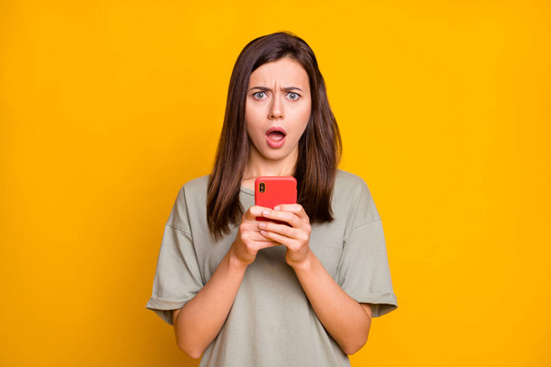 Photo of upset shocked young woman hold phone negative comment reaction isolated on yellow color background. - Fotografie, Obrázek