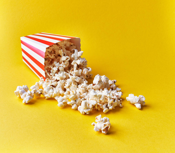  Pack of salty popcorns falling on a yellow background - Fotoğraf, Görsel