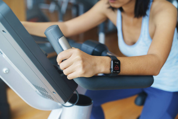 Pulse app display on smartwatch in the hands of a woman exercising in a sports club - Фото, зображення