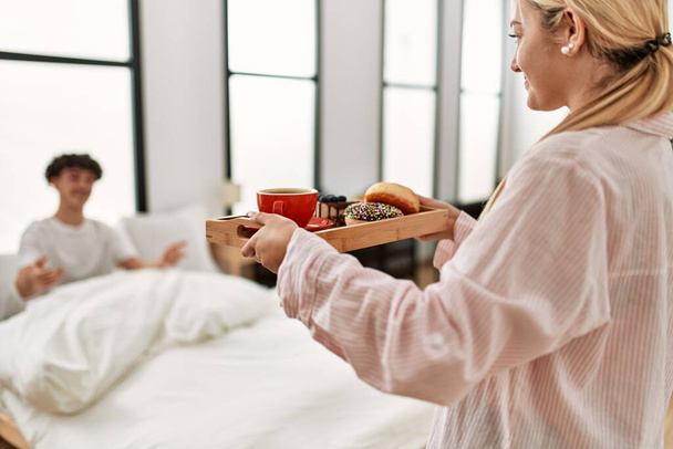 Vrouw verrassen haar vriendje met ontbijt op het bed thuis. - Foto, afbeelding