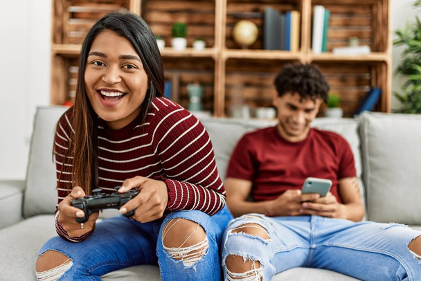 Woman playing video game and man using smartphone at home. - Photo, Image