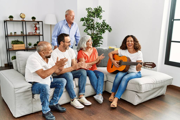 Group of middle age friends having party playing classical guitar sitting on the sofa at home. - Fotoğraf, Görsel