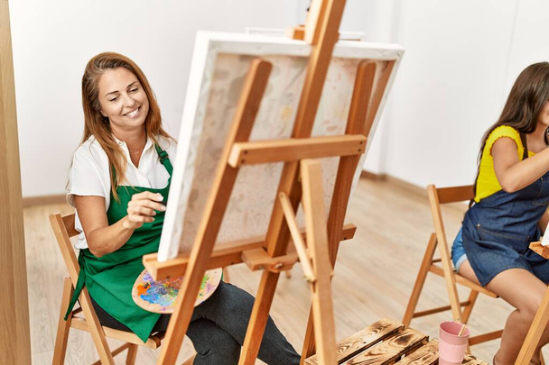 Мать и дочь улыбаются уверенно рисуя в художественной студии - Фото, изображение