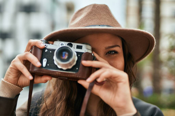 Genç İspanyol turist kadın şehirde klasik kamera kullanarak mutlu bir şekilde gülümsüyor.. - Fotoğraf, Görsel