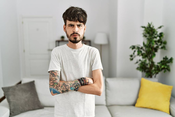 Hispanic man with beard at the living room at home skeptic and nervous, disapproving expression on face with crossed arms. negative person.  - Fotoğraf, Görsel
