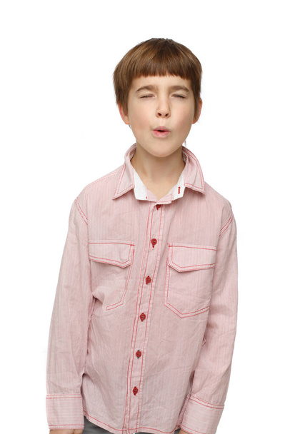 Cute little boy in casual shirt squints eyes and whistles expressing doubt isolated on white background. - Foto, Bild