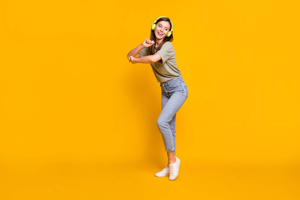 Full length body size view of pretty funny cheerful girl listening melody dancing free time isolated over bright yellow color background. - Foto, afbeelding