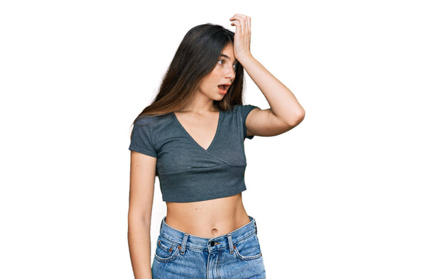 Young beautiful teen girl wearing casual crop top t shirt surprised with hand on head for mistake, remember error. forgot, bad memory concept.  - Photo, Image